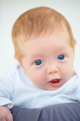 Closeup, baby and portrait with person in bedroom for childcare, holding or comfort. Infant, hope or new life for love, trust or support of milestone for future, growth or child development with bond