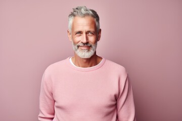 Obraz premium Portrait of a glad man in his 50s wearing a cozy sweater against a pastel or soft colors background. AI Generation