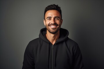 Obraz premium Portrait of a smiling man in his 30s wearing a zip-up fleece hoodie against a minimalist or empty room background. AI Generation
