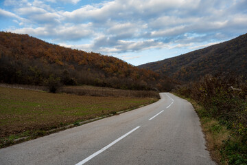 New country road in autumn.  Country road cutting through green fields in the countryside. Empty asphalt road in rural landscape with dramatic clouds. Open Road.  