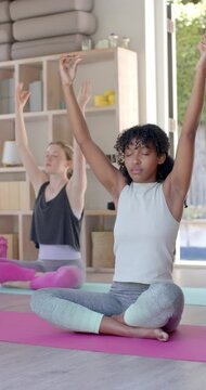 Vertical video of diverse women exercising on mats and meditating, slow motion