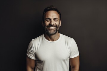 Fototapeta premium Portrait of a smiling man in his 40s sporting a vintage band t-shirt against a minimalist or empty room background. AI Generation