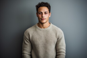 Obraz premium Portrait of a glad man in his 20s dressed in a warm wool sweater against a minimalist or empty room background. AI Generation