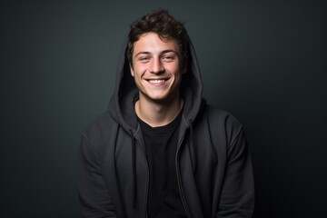 Portrait of a grinning man in his 20s wearing a zip-up fleece hoodie against a minimalist or empty room background. AI Generation