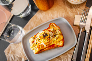 Croque Madame hot french sandwich with ham, melted cheese, fried egg and sauce.