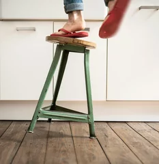 Person steht mit Flip-Flops auf einem wackeligen Hocker und fällt - Gefahren im Haushalt © Marco Martins