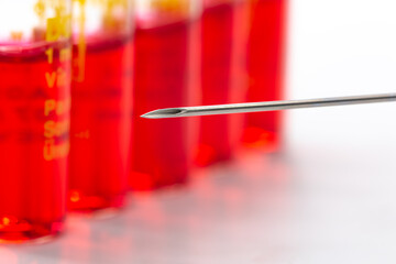 İnjection needle in selective focus. Injection ampoules of hormone B12 out of focus.
