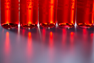 Injection ampoules of hormone B12 in selective focus. Red colored vitamin B12 liquid in injection ampoules. Background with science, biology, chemistry, medicine, health concepts. - obrazy, fototapety, plakaty