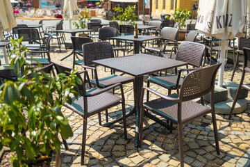 Fototapeta na wymiar Cozy empty tables and chairs of outdoor cafe in european city.