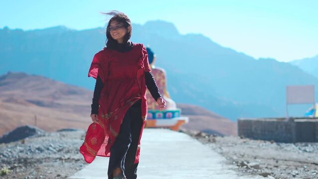 Indian girl in front of Buddha statue in Langza at Spiti Valley, India. Tourist enjoying holidays in mountains. 