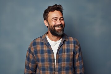 Obraz premium Portrait of a blissful man in his 30s dressed in a relaxed flannel shirt against a blank studio backdrop. AI Generation