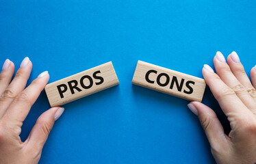 Pros vs Cons symbol. Concept word Pros vs Cons on wooden blocks. Businessman hand. Beautiful blue...