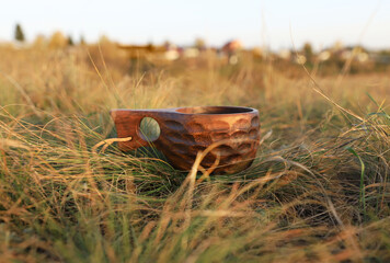 Wooden Finnish mug in nature on dry grass