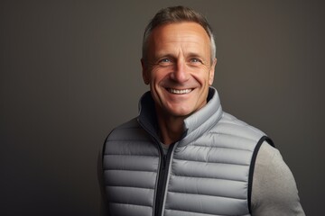 Obraz premium Portrait of a grinning man in his 40s dressed in a thermal insulation vest against a light wood minimalistic setup. AI Generation