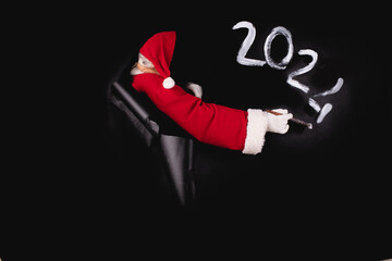 Santa Claus's hand in a white glove writes the numbers 20224 on a black paper.
