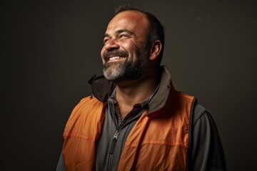 Fototapeta premium Portrait of a jovial man in his 40s dressed in a water-resistant gilet against a plain cyclorama studio wall. AI Generation