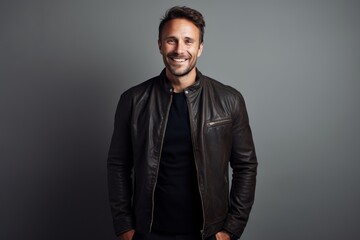 Fototapeta premium Portrait of a smiling man in his 30s sporting a classic leather jacket against a crisp minimalistic living room. AI Generation