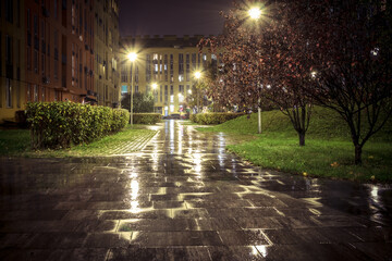 Night park paths and colored houses on a rainy autumn night. Night paths, benches, lanterns in a...