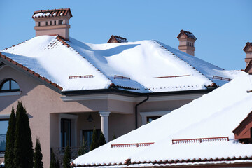 Closeup of house roof top covered with snow in cold winter. Tiled covering of building in...