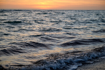 Naklejka premium Ocean sunset landscape with soft evening sea water waves crushing on sandy beach