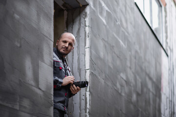 Professional industrial photographer with camera in hands at construction site.