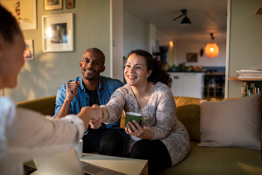 Mixed couple having a conversation with insurance saleswoman at home