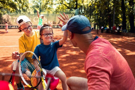 Young boy shares a joyful moment with his coach during tennis practice