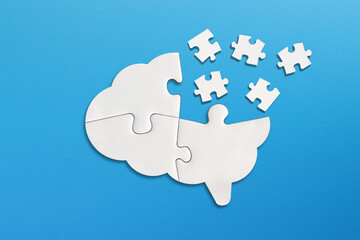 Brain shaped white jigsaw puzzle on blue background. Missing piece of the brain puzzle. Mental health and problems with memory.