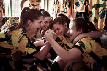 Female soccer players huddle together in unity in the locker room