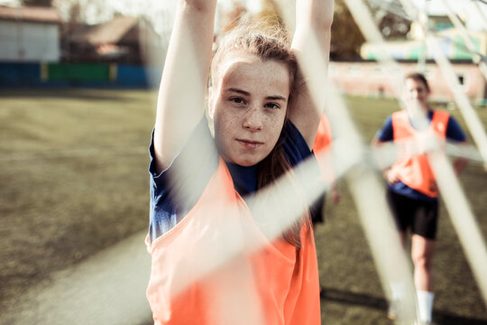 Determined female football player raises her arm in confidence on the field