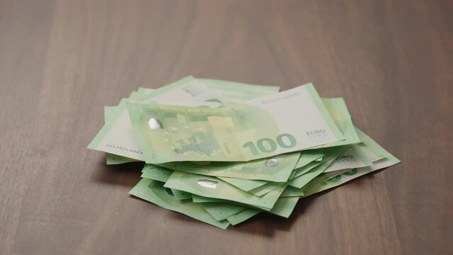 Pile stack of hundred euro bills on walnut table slide shot