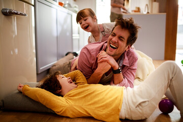 Happy young dad having fun with his kids on the floor at home