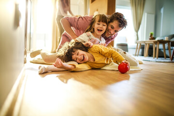 Happy young dad having fun with his kids on the floor at home