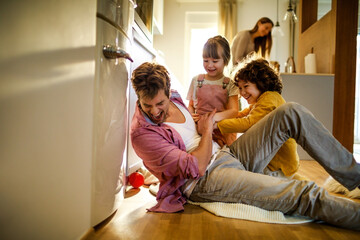 Happy young dad having fun with his kids on the floor at home