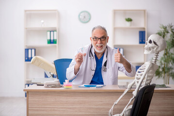 Old male doctor examining skeleton in the clinic