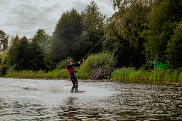 Wakesurfer on a board rides on the waves on the lake