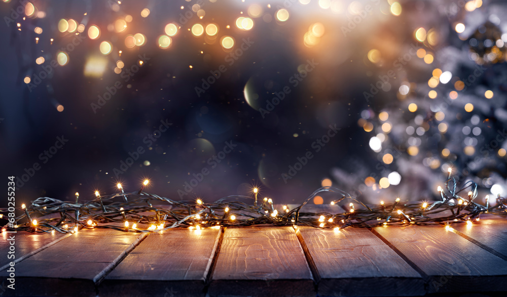 Wall mural christmas - defocused string light on rustic wooden table in the night with abstract tree