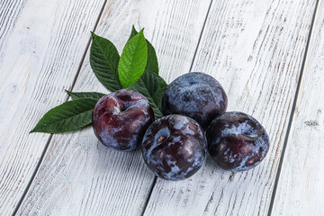 Raw purple plums heap with leaves