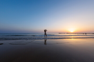 silhouette of a woman walking along the seashore. Spiritual Peace Meditation. A happy girl walks along the seashore against the backdrop of sunset.
