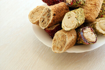 Many rolls of turkish delight with different flavors and fillings in white plate on table. Cuts of...