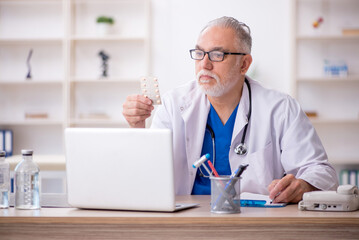 Old male doctor working in the clinic