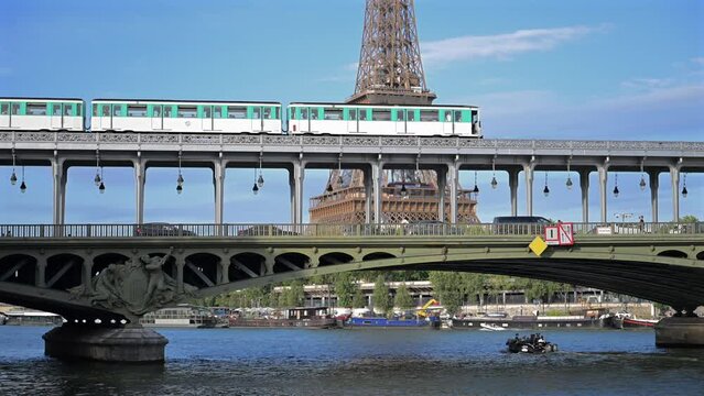 Paris, France - July 9, 2023 : day view of the parisian urban subway (metro, metropolitain) passes over a bridge (pont de Bir-Hakeim Passy line 6) with the Eiffel Tower (Tour Eiffel) in the background