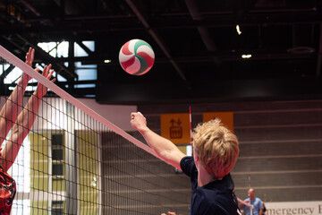 Volleyball player punching the ball over the net