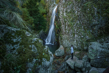 Woman standing at waterfall called Poco do Inferno with water pool during autumn time, Manteigas,...