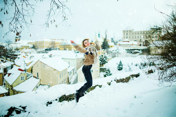Happy woman jump, enjoy snowfall in beautiful Prague city, enjoying winter holidays