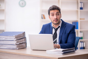 Young male employee and too much work in the office