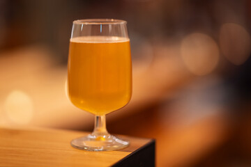 A glas of craft beer standing och a bar with a bokeh background.