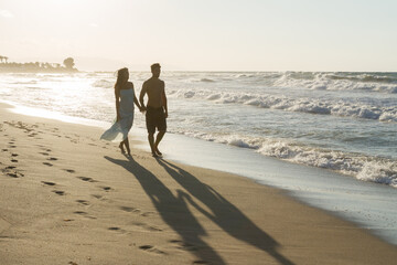 Young couple enjoys walking on a hazy beach at dusk.