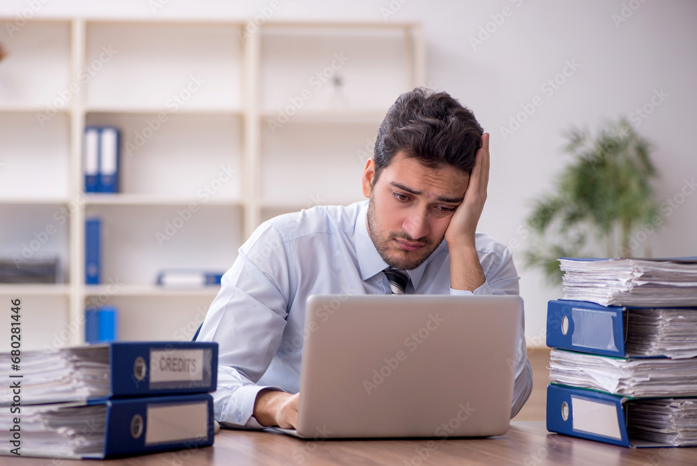 Wall mural Young male employee and too much work in the office