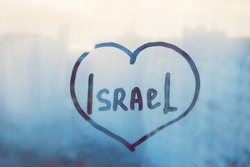 Foggy glass on window with written finger word Israel in heart shape on wet window